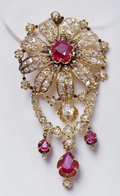 a close up of a brooch with red and white stones on it