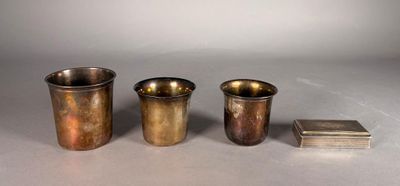 three silver cups and a book are sitting on a table