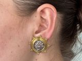 the ear of a woman wearing a pair of earrings with a coin on it