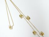 two gold necklaces on a white background one has a bird and the other has a flower