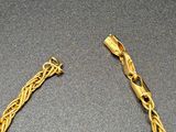two pieces of gold chain on a gray surface with a black background