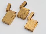 trois briquets dorés posés les uns sur les autres sur une surface blanche