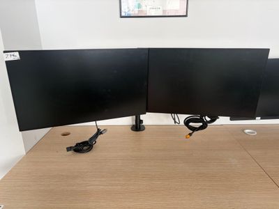 two computer monitors sitting on top of a wooden desk