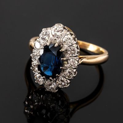a close up of a blue sapphire and diamond ring on a black surface