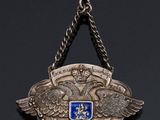 a silver and blue medal hanging from a chain on a black background