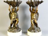 paire de statues en bronze représentant des chérubins tenant des feuilles, sur des socles en marbre