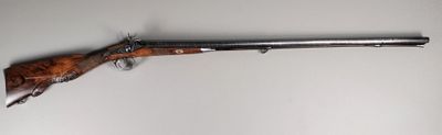 Un vieux fusil est accroché au mur d'une pièce.