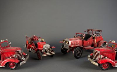 four red fire trucks are lined up in a row on a gray surface