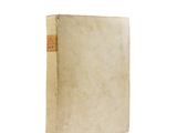 an old book sitting on top of a white table next to a white wall