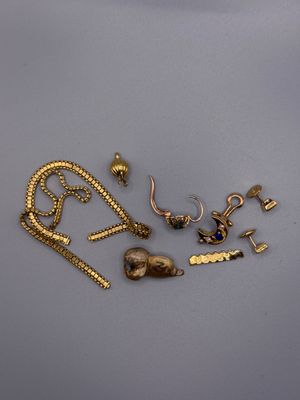quelques bijoux en or sont posés sur une table, à côté d'une paire de ciseaux