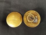 a close up of a gold pocket watch on a black surface
