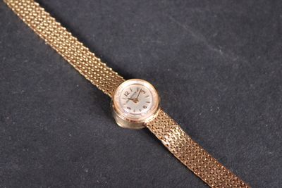 une montre en or, attachée à une chaîne, posée sur une surface noire