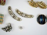 many different types of brooches and earrings on the table