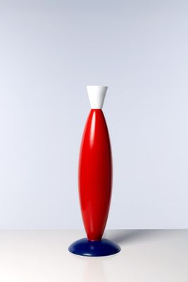 un vase rouge avec un couvercle blanc posé sur une table