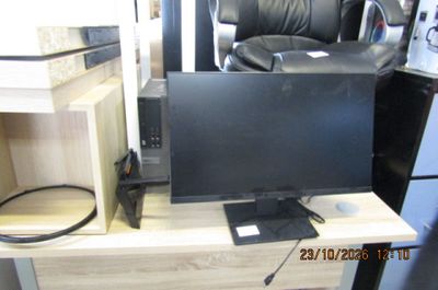 un écran d'ordinateur posé sur un bureau à côté d'un micro-ondes