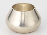 un vase en argent posé sur une table, devant un fond blanc