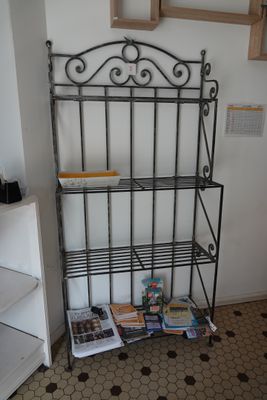 a metal shelf with magazines on it in the corner of a room