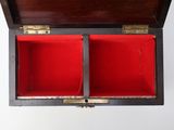 an open wooden box with red linings on a white surface