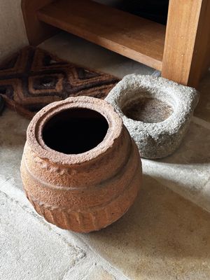 deux pots en terre cuite posés par terre à côté d'une étagère en bois