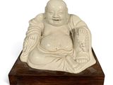 statue of a laughing buddha sitting on a wooden base
