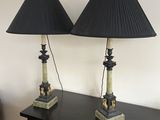 pair of black lamps on a table with a red couch in the background