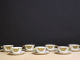six tasses et soucoupes sont alignées sur une table