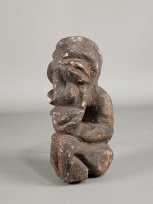 figurine of a seated man holding his hands to his face