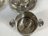 three silver tea cups and saucers sitting on a table