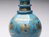 un vase bleu orné de motifs dorés, posé sur un socle