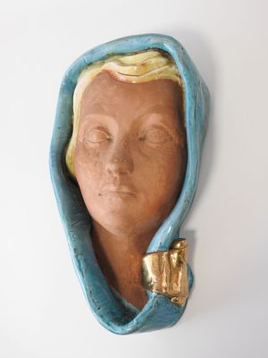 une sculpture en céramique représentant la tête d'une femme coiffée d'une capuche bleue