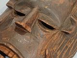 a wooden mask that is on display on the wall