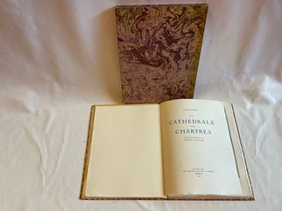 un livre ouvert posé sur un lit, à côté d'un drap blanc