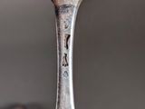 a silver spoon with a bird on it sitting on top of a table