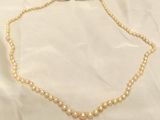 un gros plan d'un collier de perles posé sur un tissu blanc
