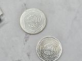 two silver coins sitting on a marble counter top