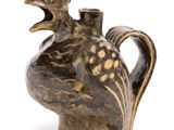 a brown vase with a bird on it on a white surface