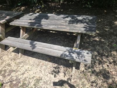 a picnic table with a bench in the middle of a field