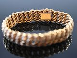 an image of a gold bracelet with a clasp on a black surface