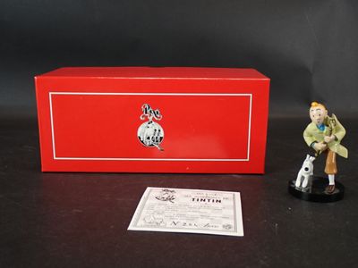 une petite figurine représentant un homme et un chien devant une boîte rouge