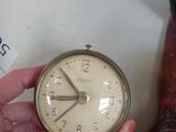 a person holding a clock in their hand next to a pair of boots