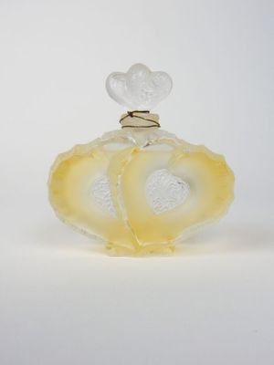 flacon de parfum en verre jaune et blanc, orné d'un cœur sur le bouchon