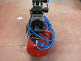a red air compressor sitting on the floor in a warehouse