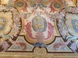painting on the ceiling of a large room with a clock on the wall