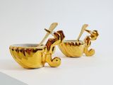pair of gold plated baby stroller cups on a white surface