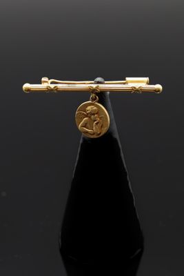 une image représentant une broche plaquée or sur laquelle est posée une pièce de monnaie