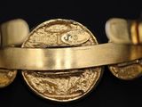 a close up of a gold bracelet with a coin on it