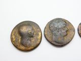 trois pièces de monnaie romaines anciennes, dont l'une porte un visage et l'autre une tête