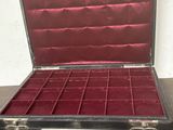 un coffret noir doublé de velours rouge posé sur une table en bois