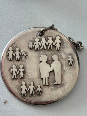a silver pendant with a picture of a family on it