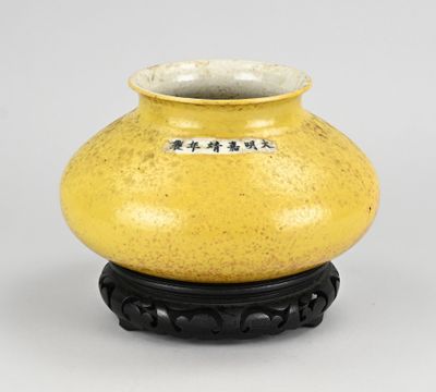 vase jaune avec un socle noir sur fond blanc, orné d'inscriptions en chinois
